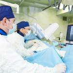Team of vascular surgeon in uniform perform operation on a patie