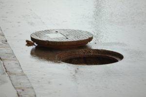 Sewer cover open on a rainy street